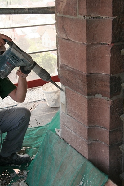 Handwerker meißeln dann die alten Sockel aus dem Mauerwerk...