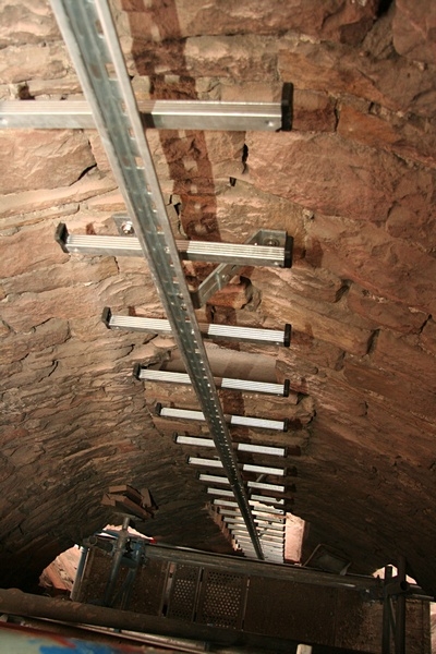 Das ist die 12 Meter hohe Leiter, die nun vom Boden des Glockenstuhles bis zum Holzboden führt.

Auf dem mittleren Steg der Leiter läuft ein Schlitten mit Sicherungshaken.
Wer künftig den Turm besteigen will, muss sich zuerst einhaken, denn ein Fall von Leiter könnte tödlich enden.
