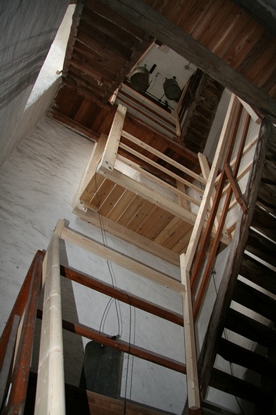 Im Turm selbst führt eine Holztreppe hinauf in die Uhrenstube und weiter zu den Glocken.