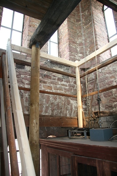 Aus dem Uhrenkasten heraus führt eine lange Stahlwelle, die die Zeiger der 4 Ziffernblätter antreibt.

Daneben sieht man die Stahlseile für das Läutewerk der Glocken.
